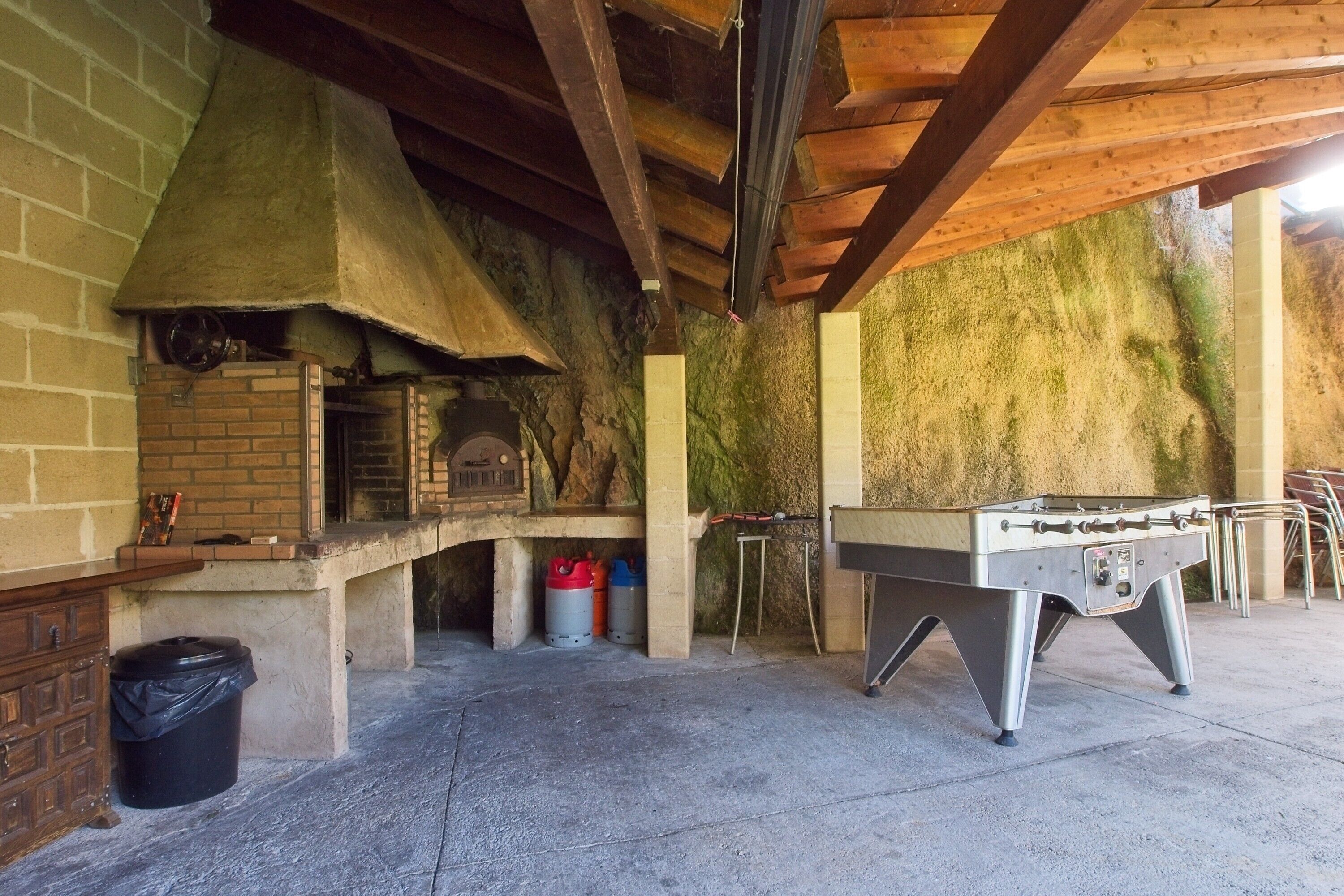 An outdoor kitchen area with a brick oven, a foosball table, and a barbecue grill.