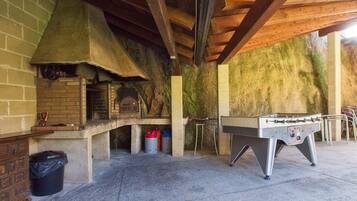 An outdoor kitchen area with a brick oven, a foosball table, and a barbecue grill.