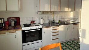 Una cocina con armarios blancos, estufa, lavaplatos y cafetera.