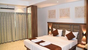 Quarto de hotel com uma cama grande, um ventilador de teto e obras de arte nas paredes.