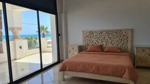 A bedroom with a large sliding glass door leading to a balcony with a view of the sea. - DAR EL NOUR | Villa pied dans l'eau | 130 m² | Rooftop avec vue exceptionnelle (Korba)