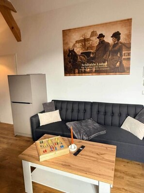 Una sala de estar moderna con un sofá negro, una mesa de centro de madera y un cartel vintage en la pared.