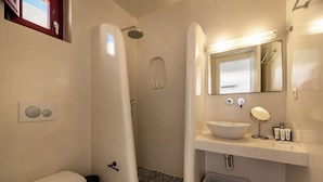 Ein Badezimmer mit Toilette, einer Dusche und einer Badewanne, einem Waschbecken mit Spiegel und einer kleinen Mülltonne.