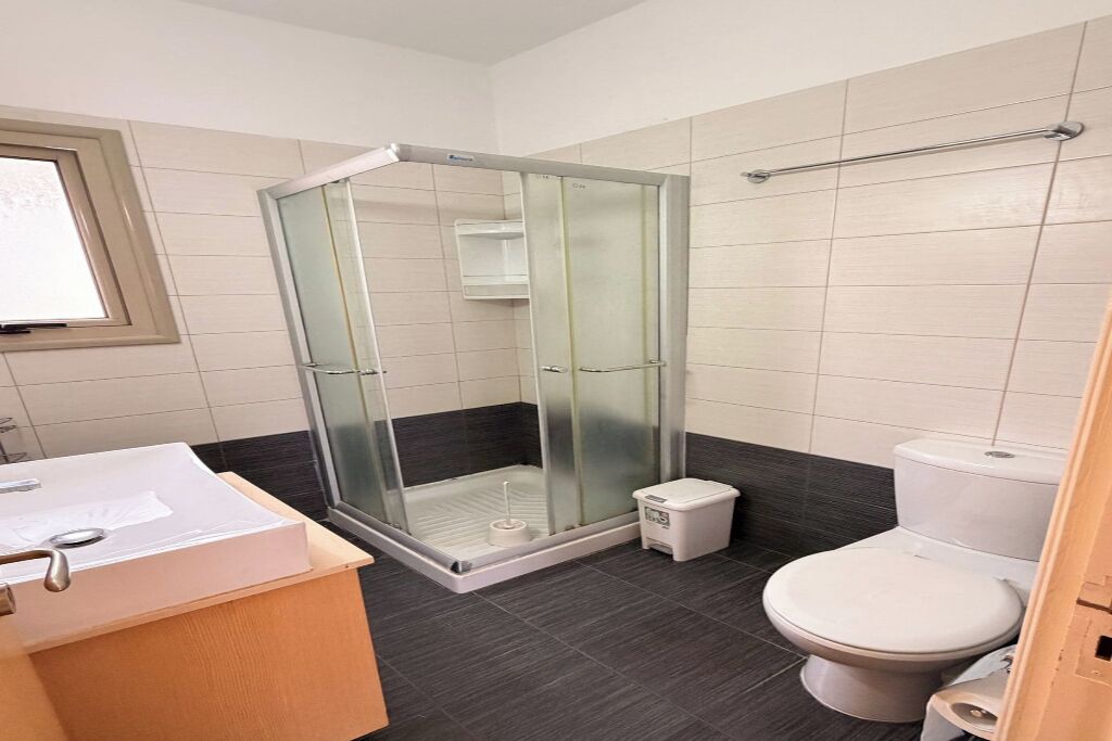 A bathroom with a glass-enclosed shower, a toilet, and a sink with a mirror.