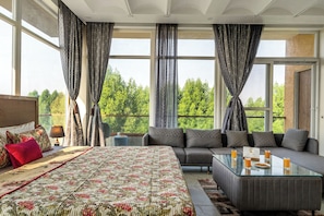 A modern bedroom with a large bed, a sofa, and a glass coffee table with drinks. - ELIVAAS Echoes by the Aravali 5BHK villa (Bassi)