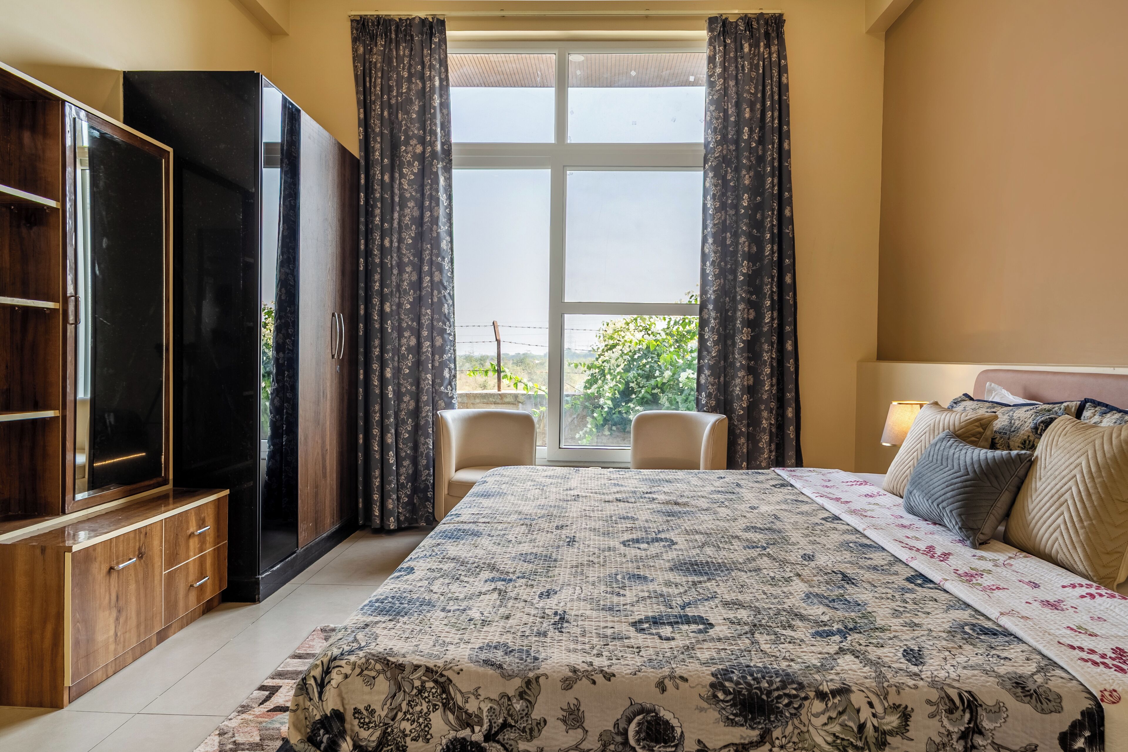 Habitación de hotel con una cama grande, televisión, armario y vistas a zonas verdes.