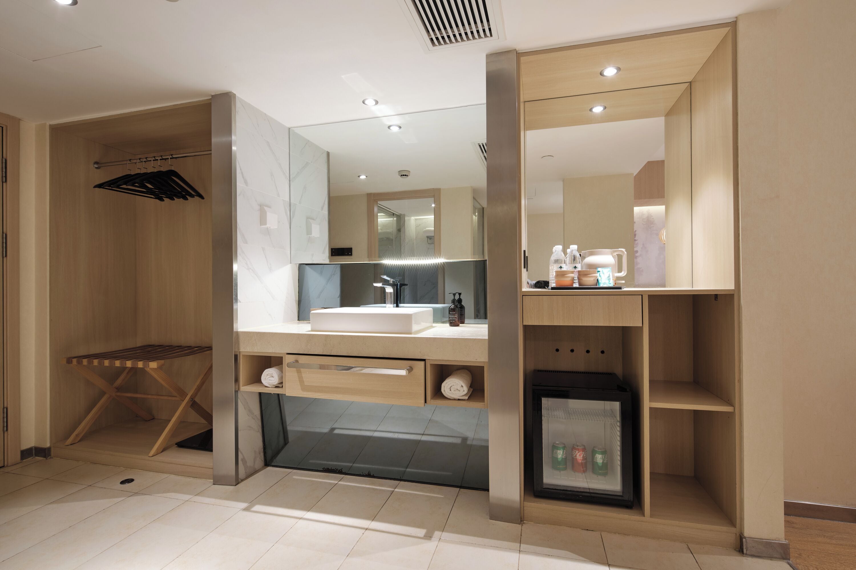 A modern bathroom with a vanity, mirror, towel rack, and a small refrigerator.