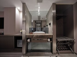 A modern bathroom with a central sink, a mirror, and a shower area.