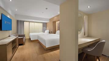 A modern hotel room with a bed, desk, chair, and a television.