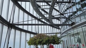 A modern interior with a curved glass ceiling, seating areas, and a central plant. - JL Hotel Shanghai LujiazuiOriental Pearl (Shanghai)