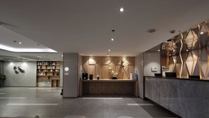 A modern reception area with a wooden reception desk, a marble counter, and a wall with geometric patterns. - JL Hotel Shanghai LujiazuiOriental Pearl (Shanghai)