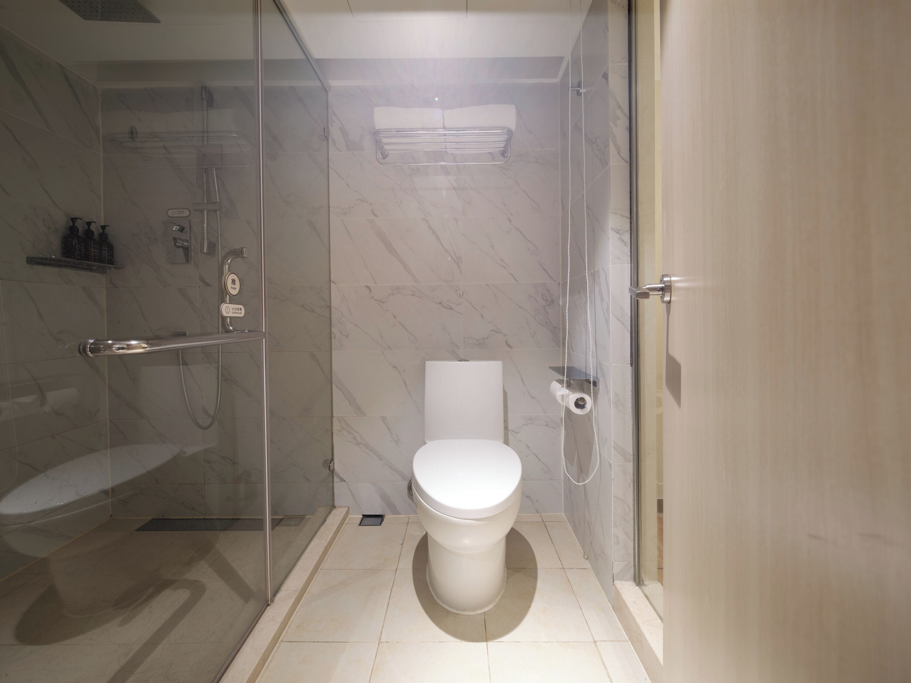 Un baño moderno con ducha de vidrio, inodoro y perchero para toallas.