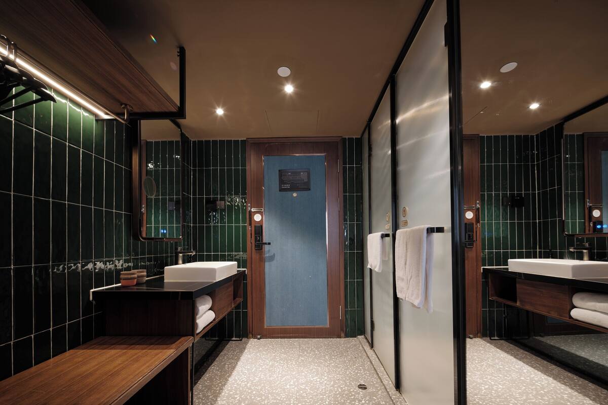 A modern bathroom with two sinks, a bench, and a mirror.