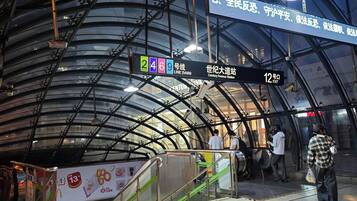 A subway station with a curved glass ceiling, signage indicating exit 12, and a digital display for Line 24.