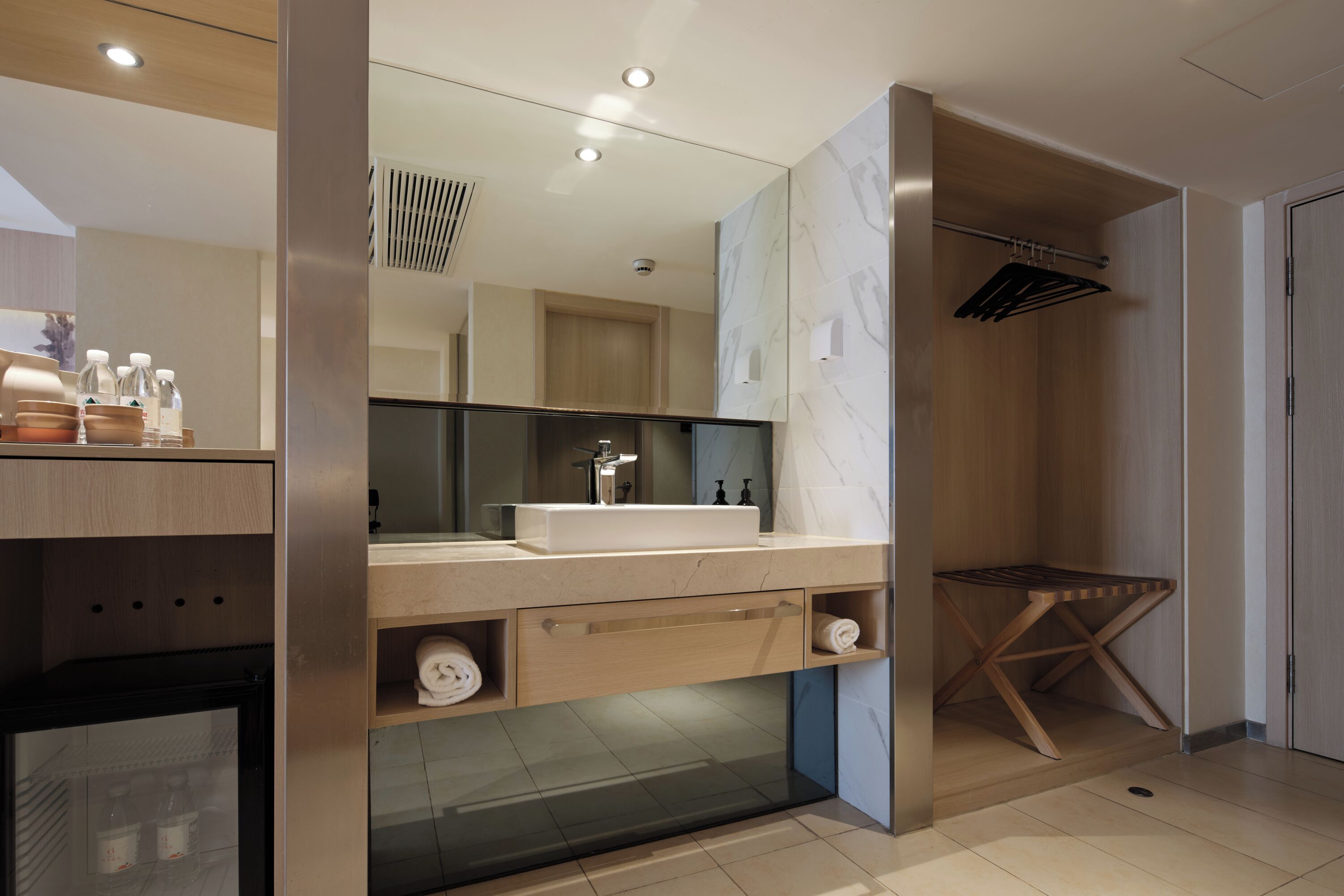 Un bagno moderno con uno specchio grande, un lavandino, un portascopevoli e una zona doccia.