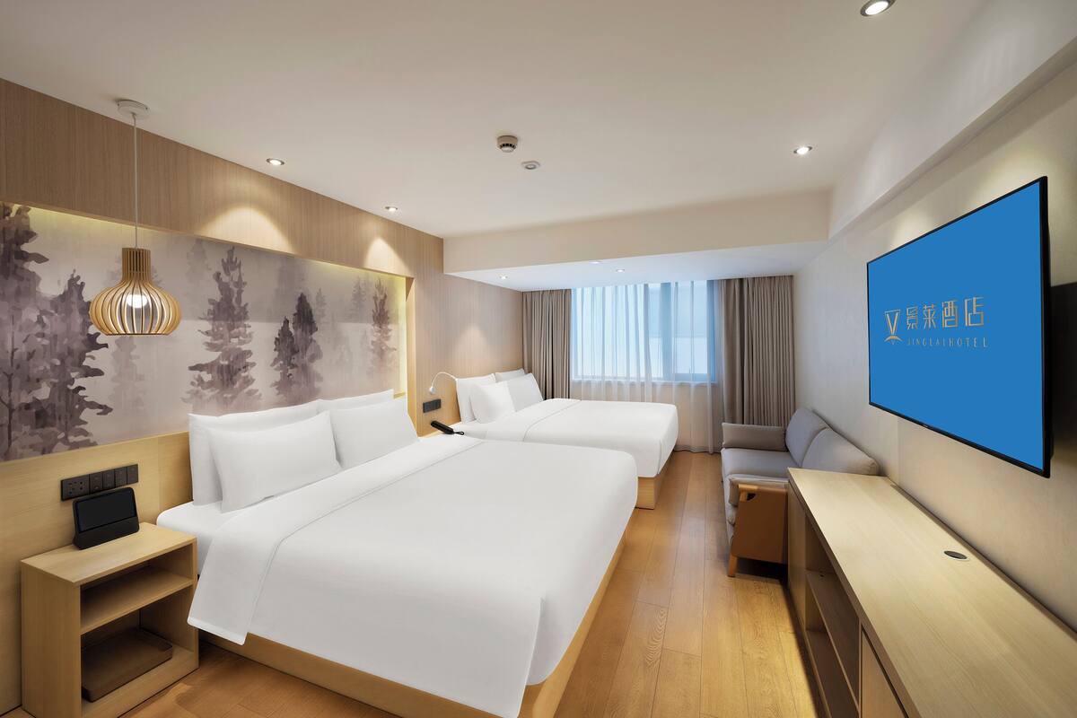 A modern hotel room with two beds, a TV, a desk, and a large window.