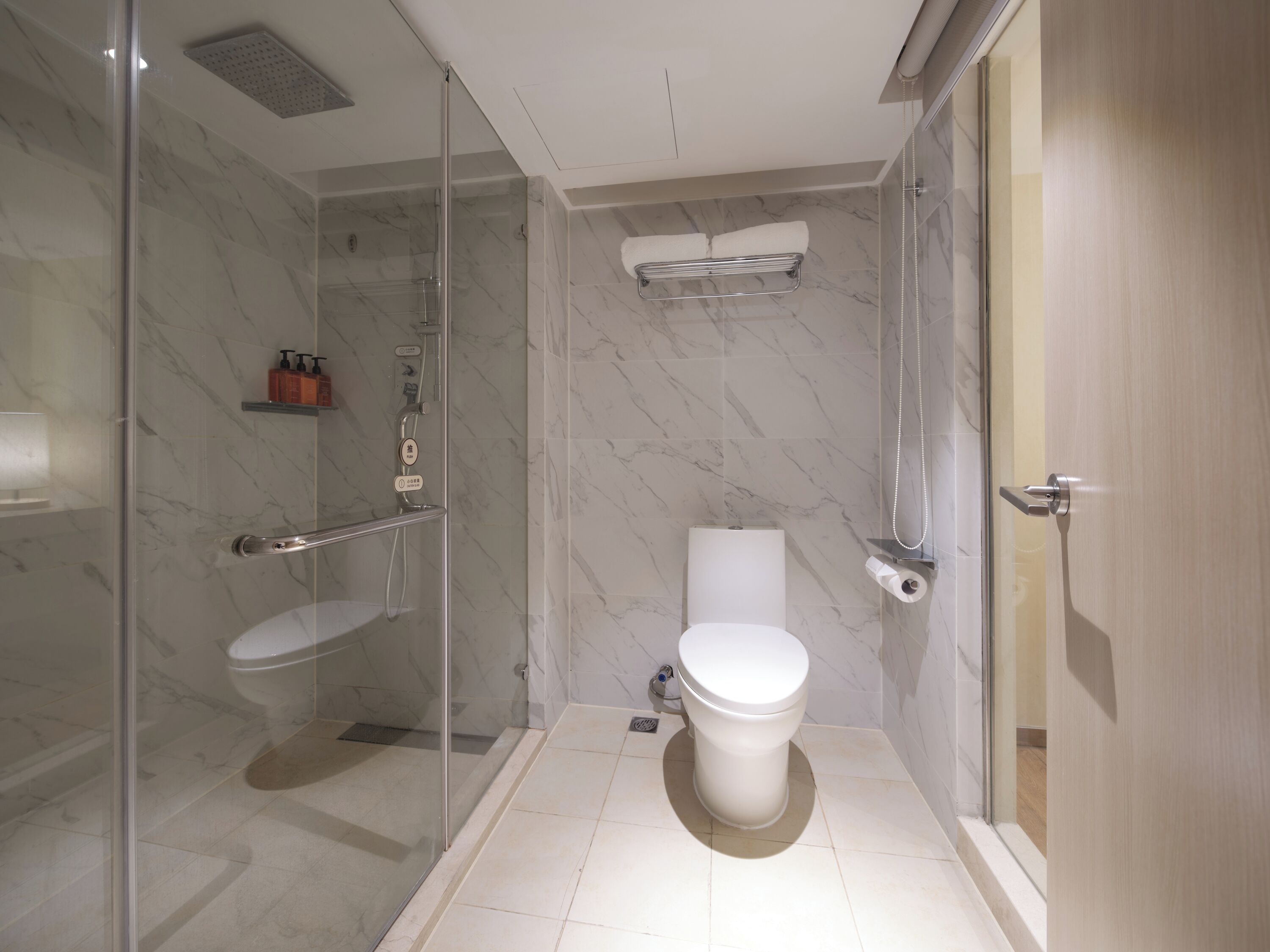 A modern bathroom with a glass shower enclosure, a toilet, and a towel rack.