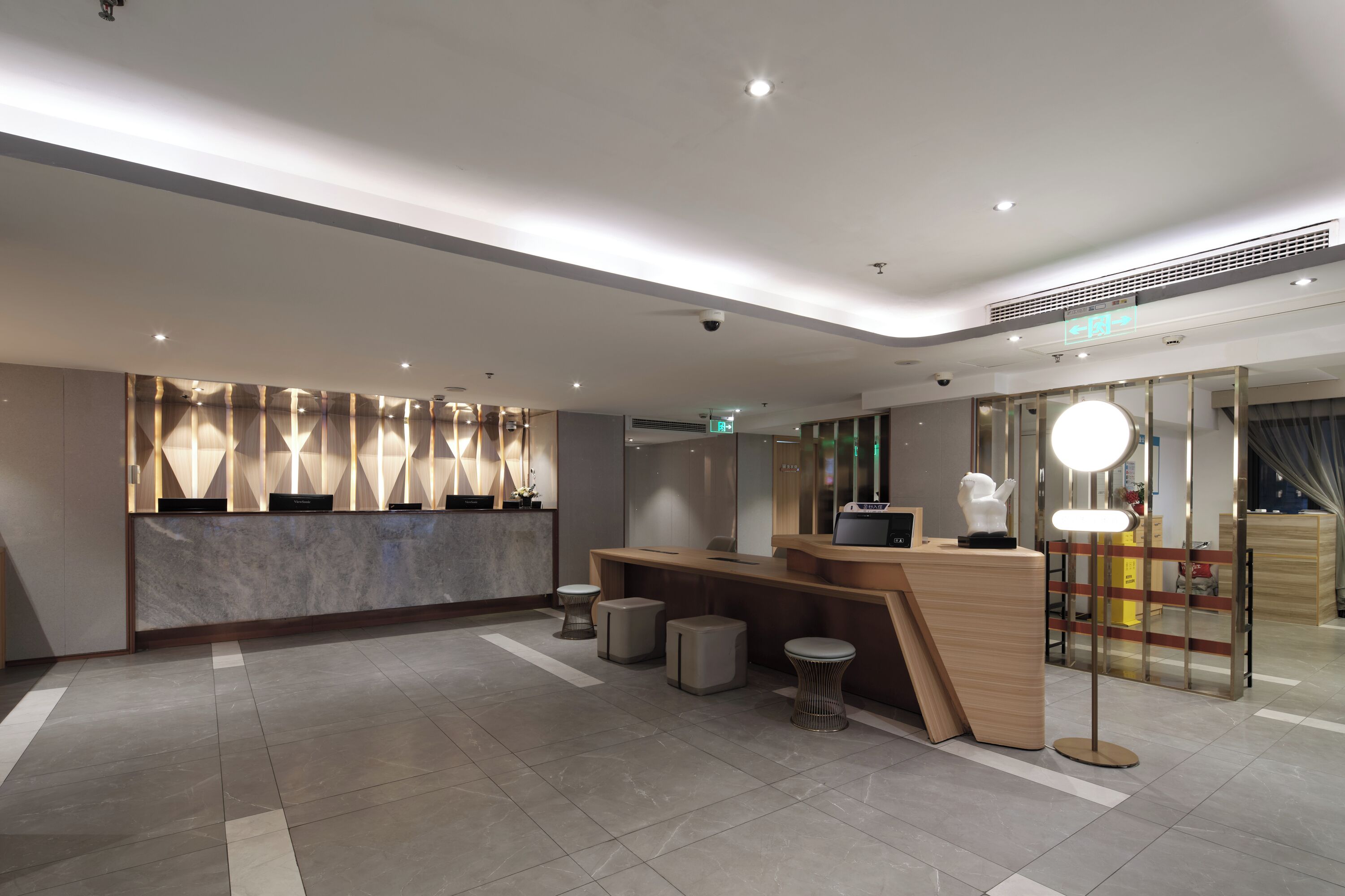 A modern reception area with a marble counter, seating, and a large mirror.
