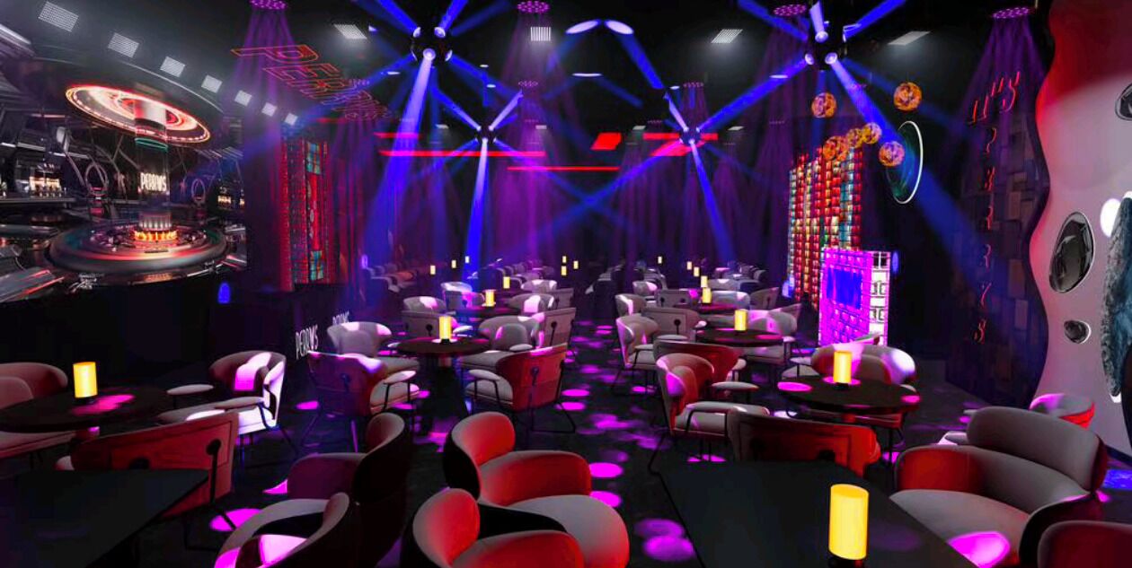 A venue with multiple tables and chairs, a DJ booth, and stage lighting.