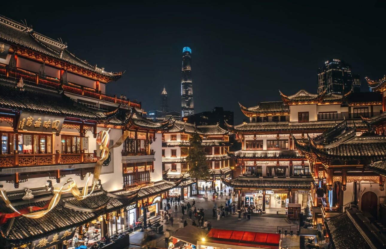 A traditional Chinese courtyard with ornate architecture and a modern skyscraper in the background.