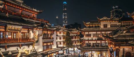 A traditional Chinese courtyard with ornate architecture and a modern skyscraper in the background.