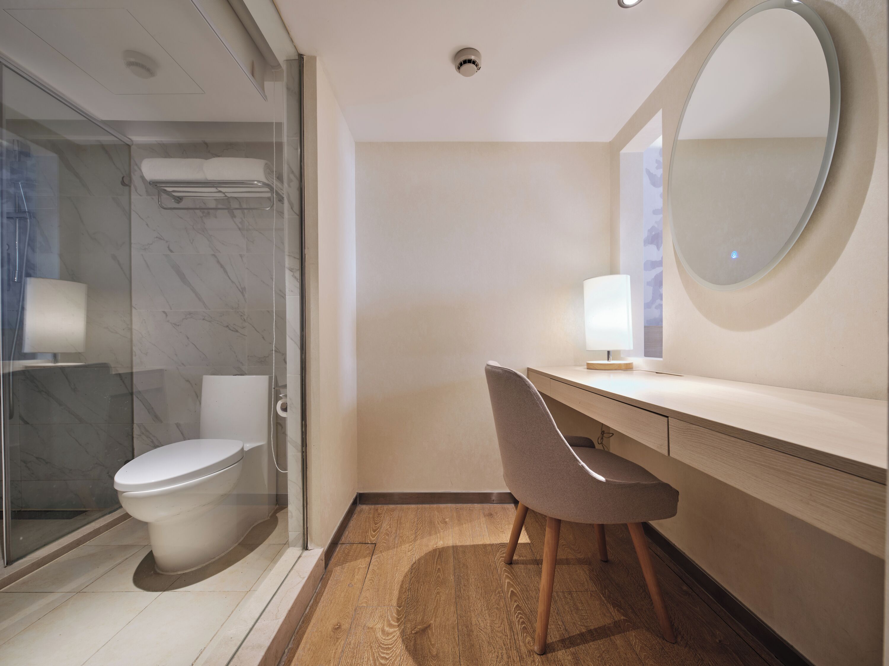 Un bagno moderno con cabina doccia in vetro, un WC, un lavabo con specchio e una sedia.