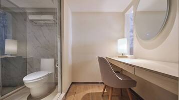 Un bagno moderno con cabina doccia in vetro, un WC, un lavabo con specchio e una sedia.
