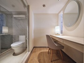 Un bagno moderno con cabina doccia in vetro, un WC, un lavabo con specchio e una sedia.