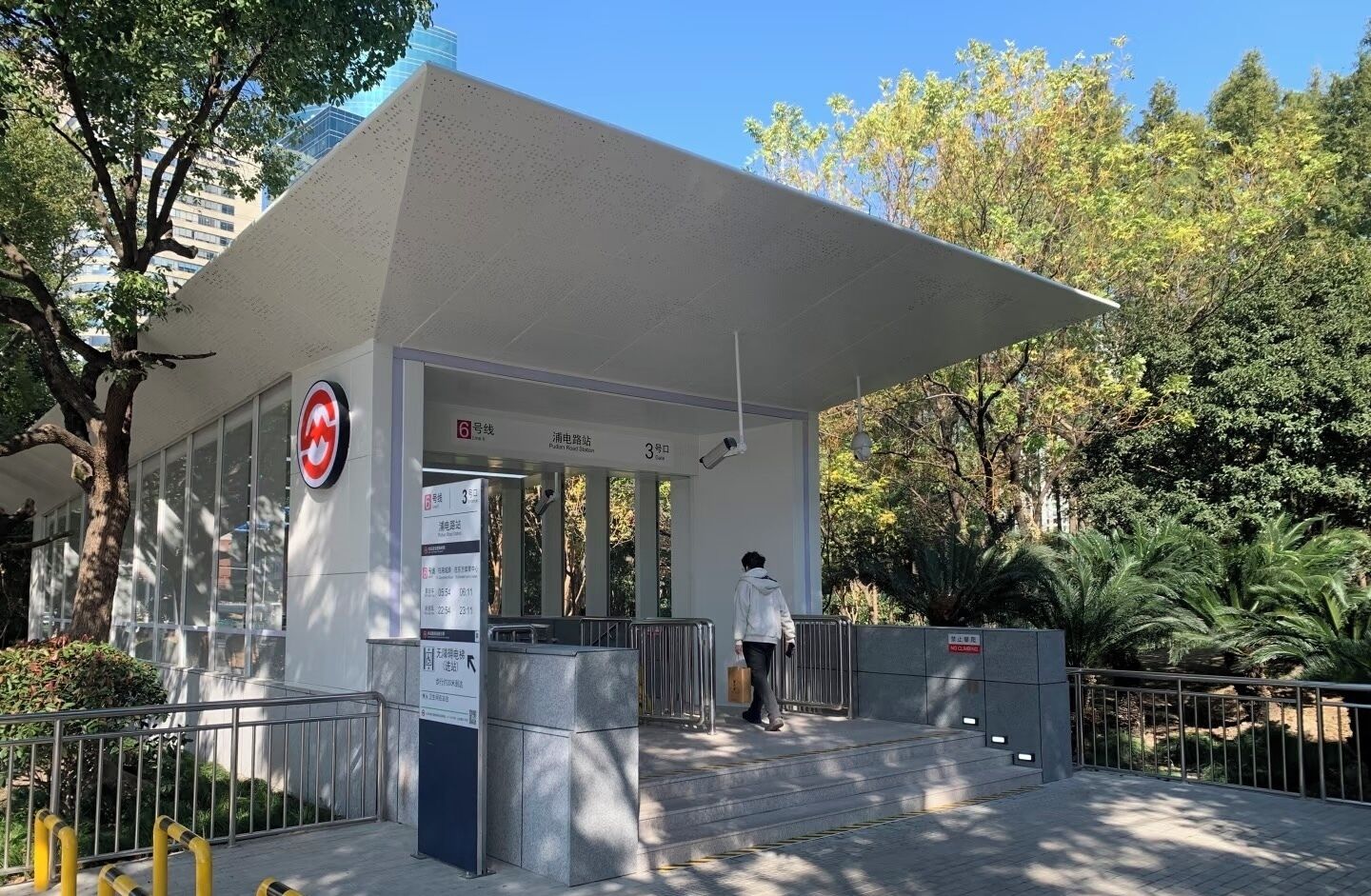 A building entrance with a sign indicating a parking area, a security camera, and a person walking towards the entrance.