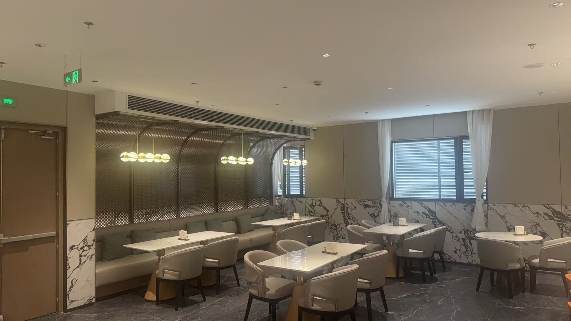 Un ristorante dall'arredamento moderno, con un'ampia scelta di posti a sedere tra cui cabine e tavoli, una parete decorata e un soffitto con illuminazione a incasso.
