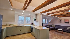 A modern kitchen with a built-in island, wooden beams, and large windows.