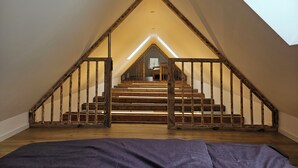 A room with a sloped ceiling, wooden staircase, and a skylight.
