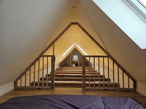 A room with a sloped ceiling, wooden staircase, and a skylight.