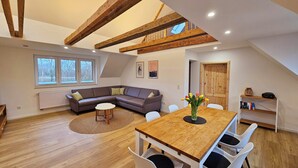 A loft-style room with a dining table, chairs, a sofa, and a radiator.
