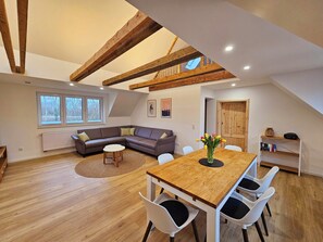 A loft-style room with a dining table, chairs, a sofa, and a radiator.