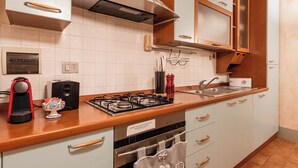 Een moderne keuken met witte kasten, een roestvrijstalen afzuigkap, een gasfornuis en houten aanrechtbladen.