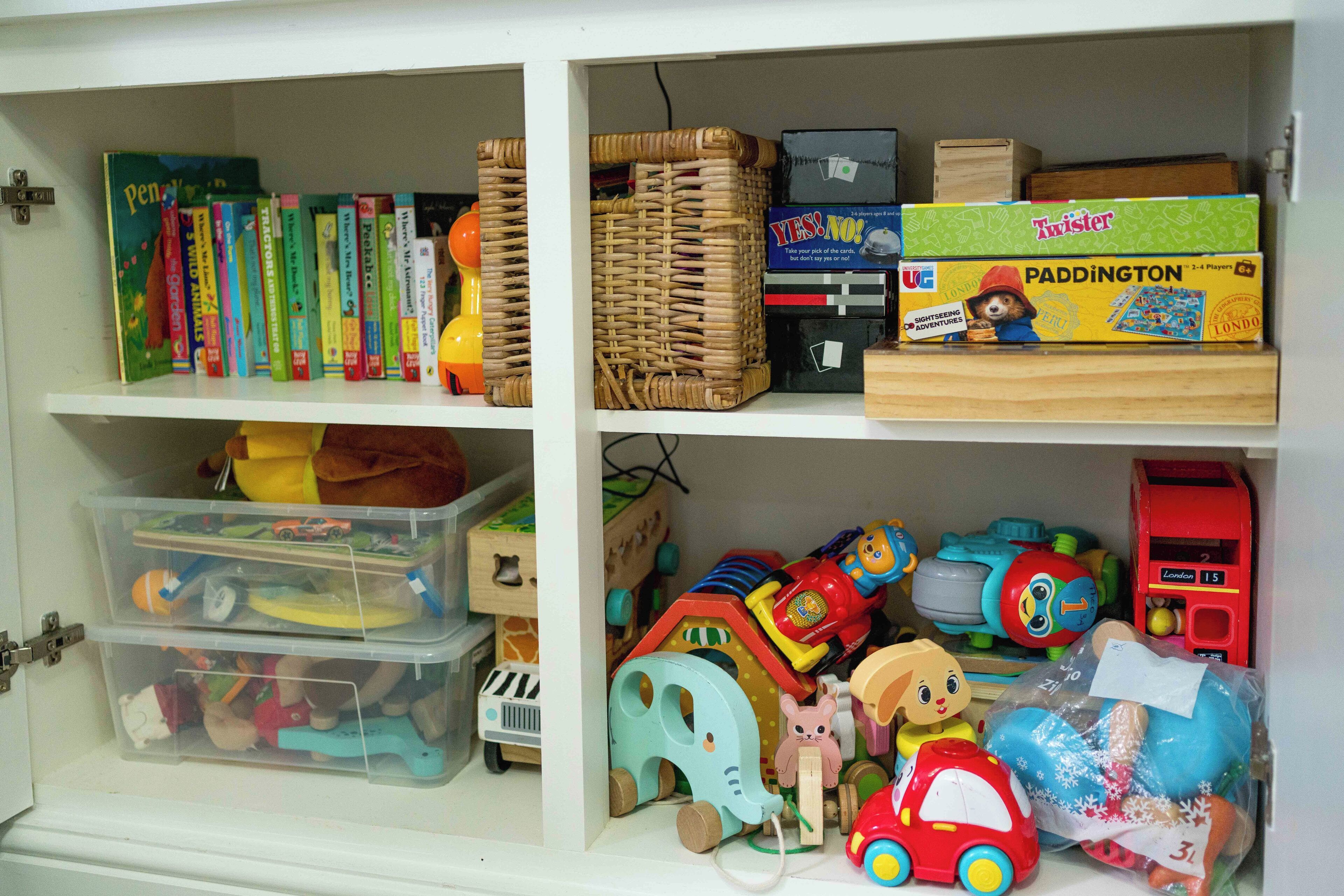 A storage unit with shelves containing books, toys, and storage bins.