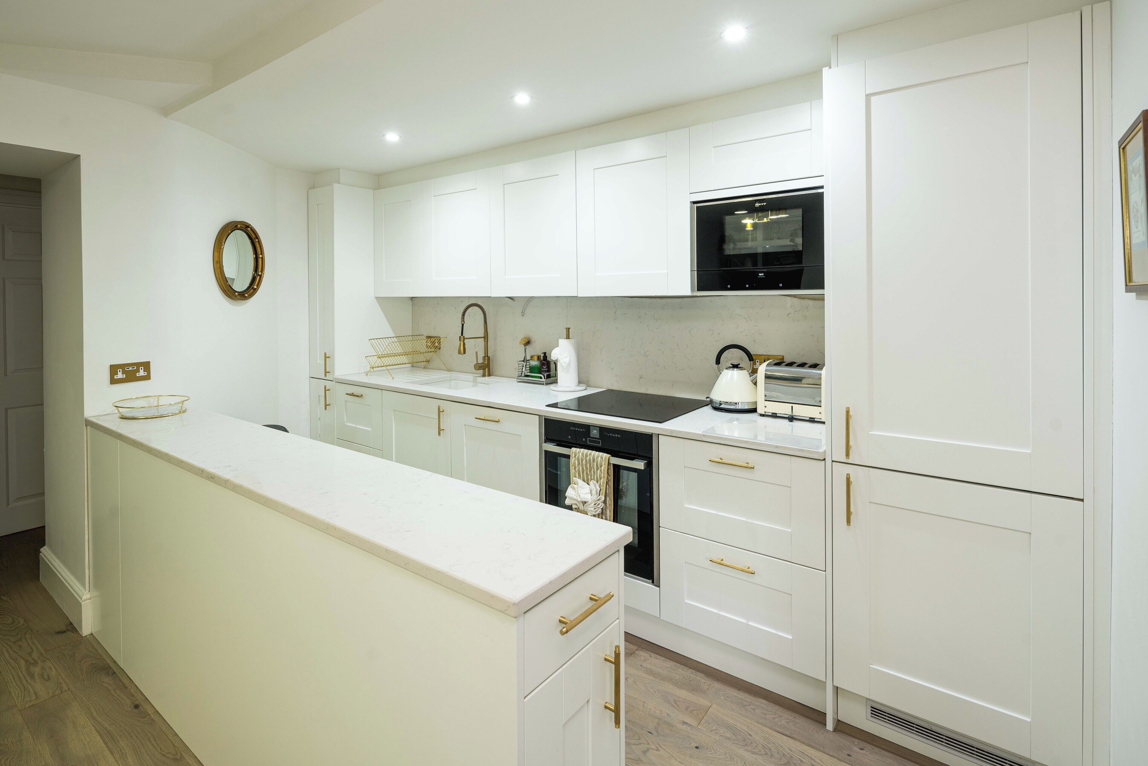 A modern kitchen with white cabinetry, a built-in oven, and a microwave.