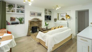 Een gezellige woonkamer met een open haard, witte meubels en een eethoek.