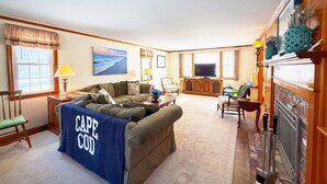 A cozy living room with a sofa, a television, and a fireplace. - New Seabury Getaway | Perfect Leaf Peeping! (Mashpee)