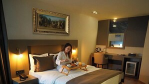 Una camera d'albergo moderna con un letto grande, comodini, una scrivania e un angolo cottura.