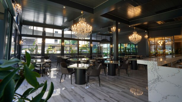 Un interno ristorante moderno con pavimento in marmo, ampie finestre e lampadari.