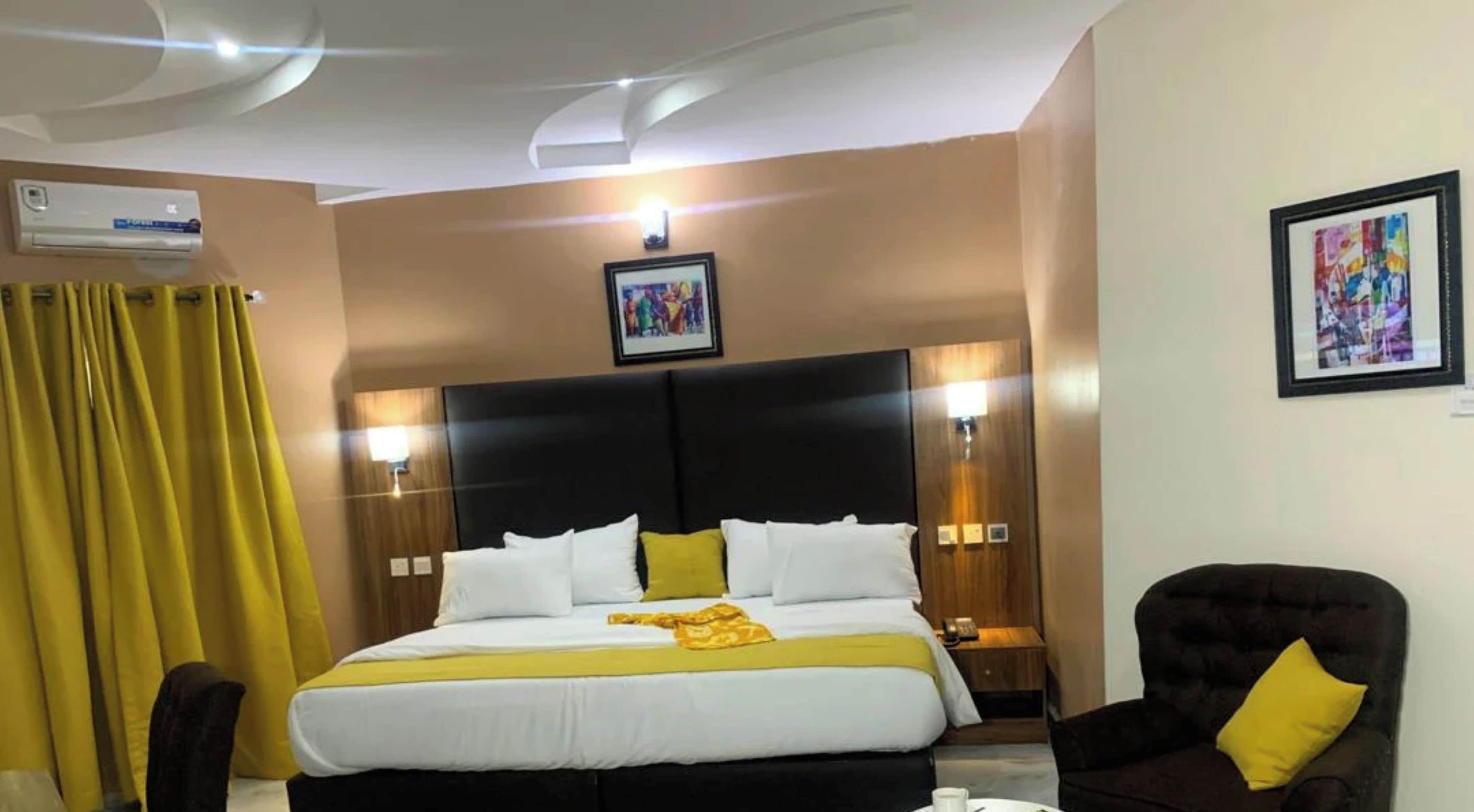 Habitación de hotel con una cama grande, una silla, un equipo de aire acondicionado y un cuadro en la pared.