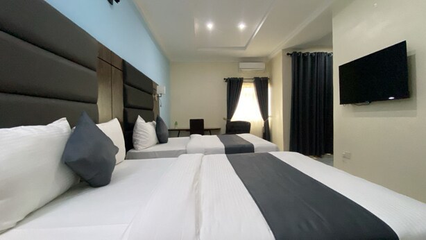 A hotel room with two beds, a flat-screen TV, a desk, and a chair. - Pearl Paradise Resort by 4E (Bonny)