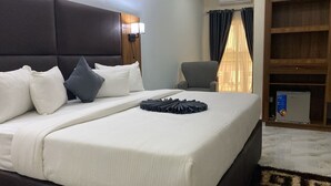 A hotel room with a large bed, a chair, a desk, and a wardrobe. - Pearl Paradise Resort by 4E (Bonny)