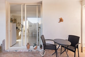 A patio with a table and chairs, a sliding glass door leading to an indoor area, and a small decorative item on the wall. - Domo Antico Borgo - Royal Room (Oristano)