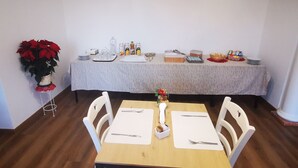 A dining area with a table set for two, a buffet table in the background, and a potted plant on the left. - Paradise B&B. Your Exclusive Refuge in Castiglione del Lago! (Panicarola)