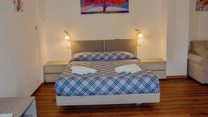 A bedroom with a bed, bedside lamps, a painting of a tree, and a chair. - Paradise B&B. Your Exclusive Refuge in Castiglione del Lago! (Panicarola)