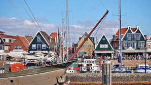 Un port où sont amarrés des bateaux, un mur de pierre et des bâtiments traditionnels aux toits en pente.