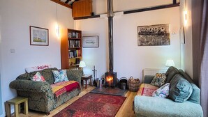 Ein gemütliches Wohnzimmer mit Kamin, Holzbalken und zwei Sofas mit Kissen.